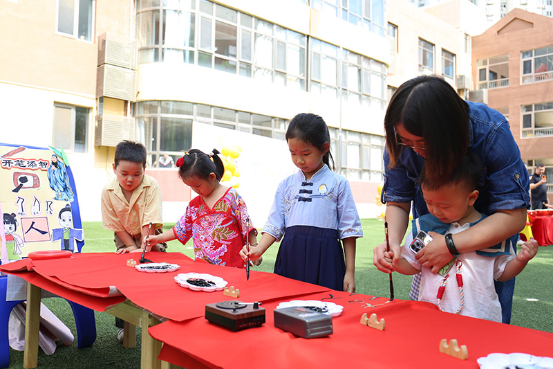 9月1日,北京市朝阳区望京新城幼儿园以“开笔启智,礼润星宝”为主题的秋季开学典礼拉开帷幕。幼儿园开展了朱砂启智、击鼓鸣智、开笔启智、盥洗礼等传统文化互动游戏,愿知礼明礼、潜心向学的种子在孩子们的心中生根发芽。图为老师带小朋友开笔启智。北京市朝阳区教委供图